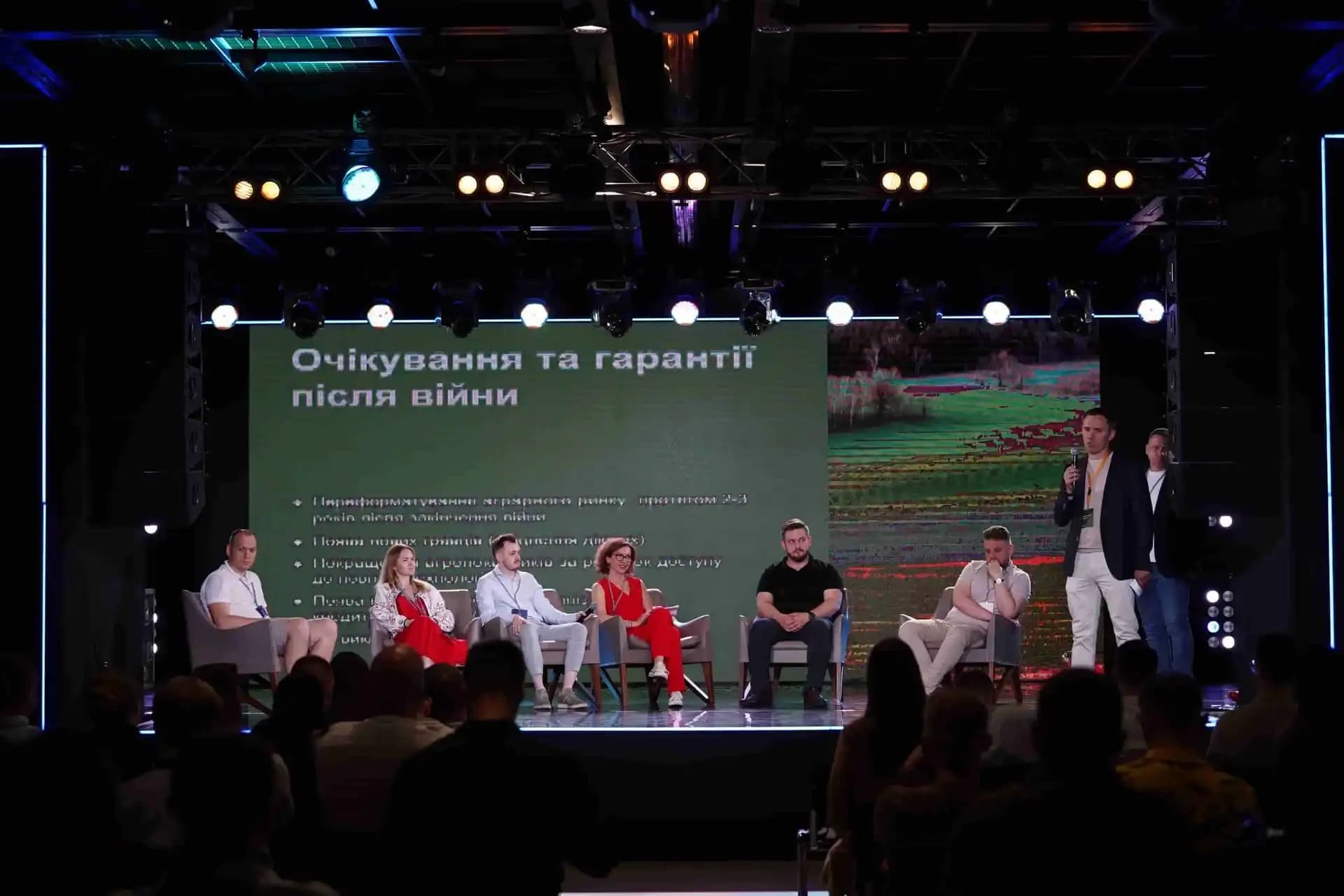Panel discussion on stage with multiple speakers seated and one standing.