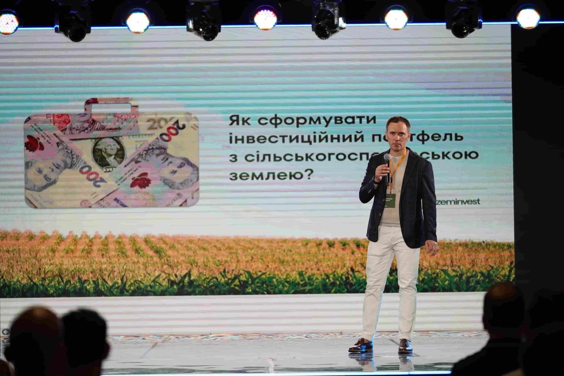 Person speaking on stage with a presentation about forming an investment portfolio with agricultural land.